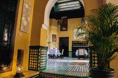 a dining room with a table and a potted plant at Riad Zidania in Meknès