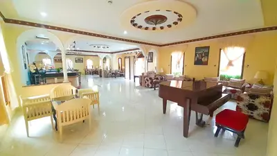 a living room with a piano and a table and chairs at Hôtel Relais Saiss in Sefrou