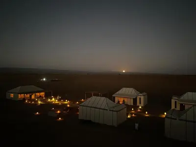 a group of buildings in the desert at night at Desert Luxury Camp Erg Chigaga in El Gouera