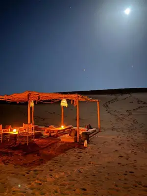 a wooden shelter on the beach at night at Desert Luxury Camp Erg Chigaga in El Gouera
