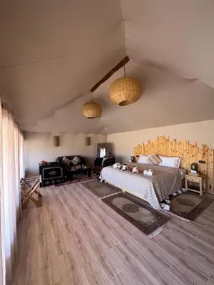 a bedroom with a bed and a living room at Desert Luxury Camp Erg Chigaga in El Gouera
