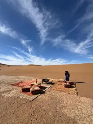 a man standing in the middle of a desert at Desert Luxury Camp Erg Chigaga in El Gouera