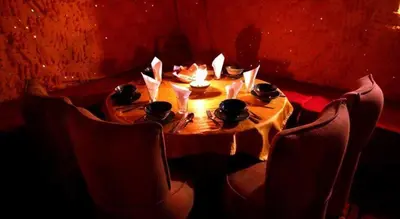 a wooden table with chairs and a table with candles at Bivouac Karim Sahara in Zagora