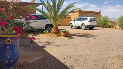 a white car parked in a parking lot with a palm tree at Camping Bassou in Nkob
