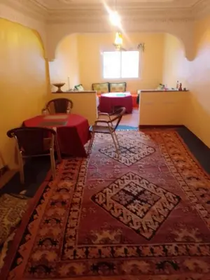a room with a table and a rug on the floor at Maison D'hote Amazir DADES in Boumalne