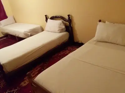 two beds in a small room with white sheets at Maison D'hote Amazir DADES in Boumalne
