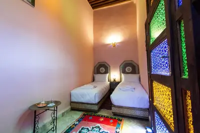 two beds in a room with a door and a rug at Dar Mchachti fes in Fès