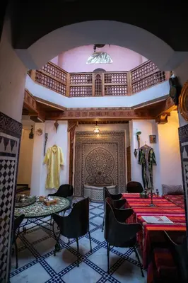 a room with two tables and chairs and a wall at Dar Mchachti fes in Fès