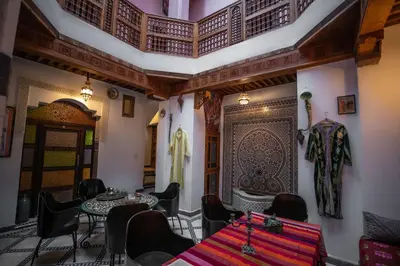 a dining room with tables and chairs and a wall at Dar Mchachti fes in Fès