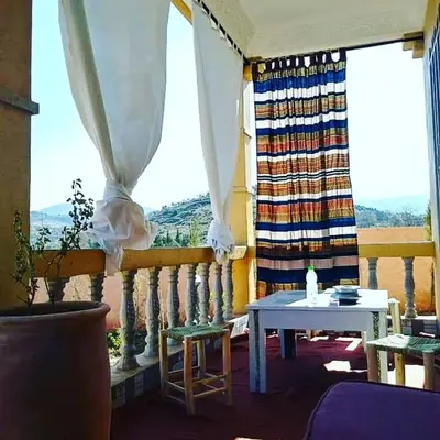 a room with a balcony with a table and a window at Le petit Jardin in Demnat