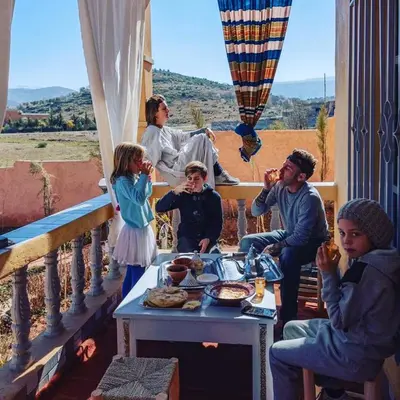 a group of people sitting around a table on a porch at Le petit Jardin in Demnat