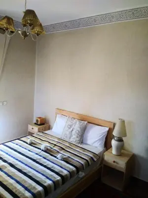 a bedroom with a bed with a blue and white comforter at Le petit Jardin in Demnat