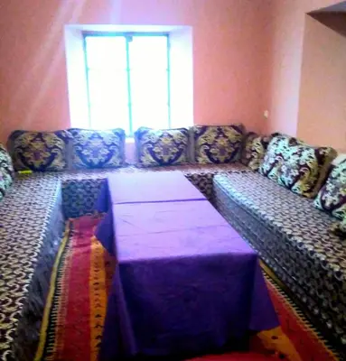 a living room with a couch with a table at LE JARDIN DES GRENADIERS in Skoura