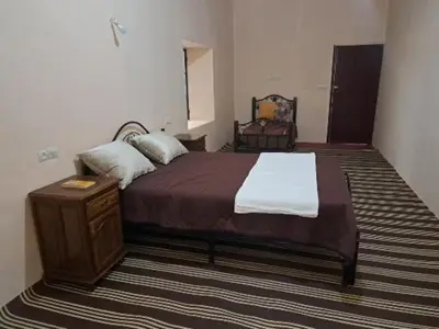 a bedroom with a large bed and a wooden table at LE JARDIN DES GRENADIERS in Skoura
