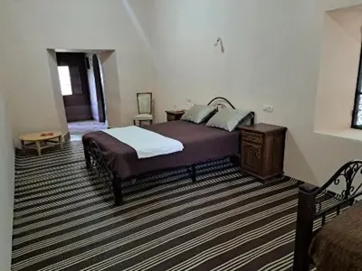 a bedroom with a bed and a table and a chair at LE JARDIN DES GRENADIERS in Skoura
