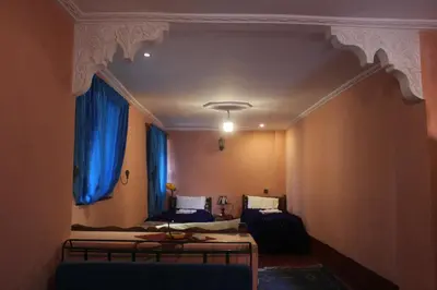 a room with two beds and blue curtains at Chez Yacob kasbah in Agdz