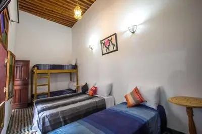 a bedroom with two twin beds and a table at DAR MILOUDA RCIF in Fès