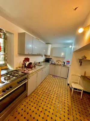 a kitchen with white cabinets and a checkered floor at Dar Jardin Majorelle Fez in Fès