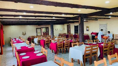 a dining room with tables and chairs with red tablecloths at Hotel Meteorites Boulaajoul in Zaida