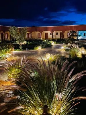 a building with lights in a courtyard at night at Hotel Meteorites Boulaajoul in Zaida