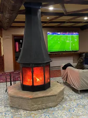 a fireplace in the middle of a room with a television at Hotel Meteorites Boulaajoul in Zaida