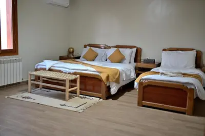 a bedroom with two twin beds and a stool at Hotel Meteorites Boulaajoul in Zaida
