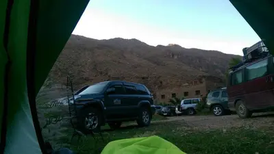 a view from inside a tent of cars parked in front of mountains at Auberge Le Festival Todra Gorge in Aït Baha