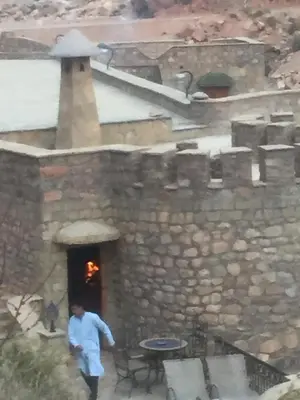 a man walking in front of a stone building at Auberge Le Festival Todra Gorge in Aït Baha