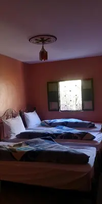 two beds in a bedroom with a window at Dar Angour Tacheddirt in Tacheddirt