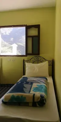 a bedroom with a bed with a window and a bedspread at Dar Angour Tacheddirt in Tacheddirt