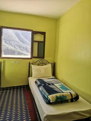 a small bedroom with a bed and a window at Dar Angour Tacheddirt in Tacheddirt