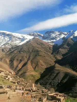 a village on a mountain with snow covered mountains at Dar Angour Tacheddirt in Tacheddirt