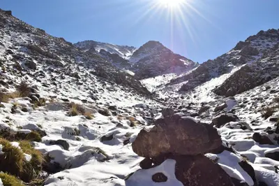 a snowy mountain with the sun in the background at Dar Angour Tacheddirt in Tacheddirt