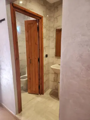a bathroom with a wooden door and a sink at La Rose De Sable in Aït Ben Haddou