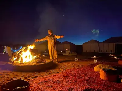a man standing in front of a fire at Erg Chegaga nomad tour in Mhamid