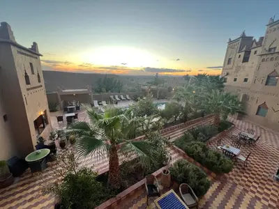 a view of a courtyard with palm trees and buildings at Kasbah Ait BenHadda in Skoura
