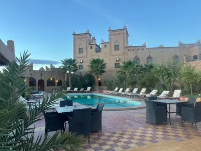 a resort with a pool and chairs and a building at Kasbah Ait BenHadda in Skoura