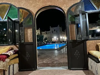 an open door to a swimming pool at night at Kasbah Ait BenHadda in Skoura