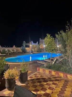 a pool at night with a checkeredkered floor and a swimming pool at Kasbah Ait BenHadda in Skoura