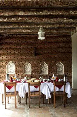 a dining room with a table and chairs and a brick wall at Kasbah Illy in Demnat