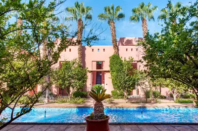 a house with palm trees in front of a pool at Hapimag Resort Marrakesh in Douar Soukkane