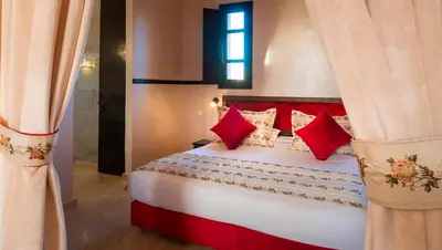 a bedroom with a large bed with red pillows at Hapimag Resort Marrakesh in Douar Soukkane