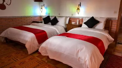 a bedroom with two beds with white and red sheets at Dar Essyaha in Ait Ben Ali