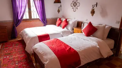 a bedroom with two beds with red and white sheets at Dar Essyaha in Ait Ben Ali