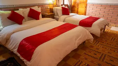 two beds with red and white sheets in a room at Dar Essyaha in Ait Ben Ali