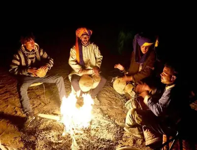 a group of people sitting around a fire at Camp Sahara Majestic in Mhamid
