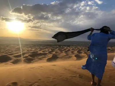 two people walking in the sand in the desert at Camp Sahara Majestic in Mhamid