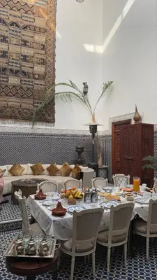 a dining room with tables and chairs with food on them at Riad Meyssane Fès in Fès