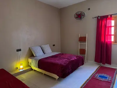a bedroom with a bed and a red window at Riad Tazoulte in Agdz