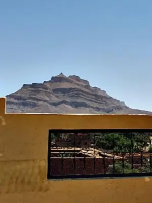 a building with a window with a mountain in the background at Riad Tazoulte in Agdz